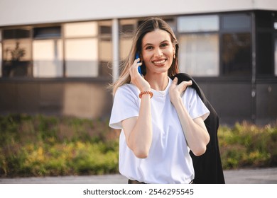 Beauty short hair woman holding jacket over shoulder. Professional businesswoman happily answering a phone call near office. Happy caucasian female using a mobile phone to communicate with partners. - Powered by Shutterstock