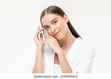 Beauty shot portrait of attractive Caucasian woman with smooth skin looking at camera on white isolated background in light studio