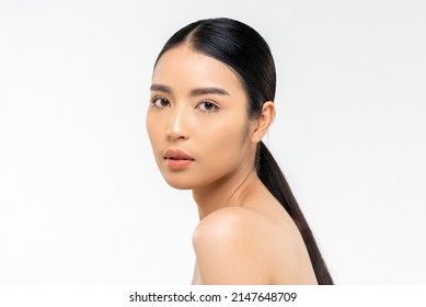 Beauty shot of pretty young Asian woman with clean face skin looking at camera during spa session against white background