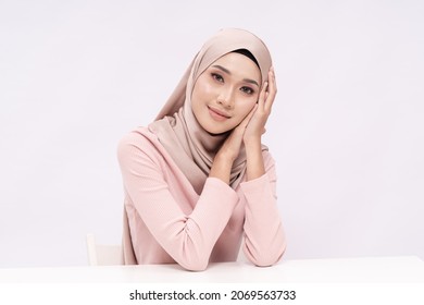 A beauty shot of a pretty young hijab girl with smooth glowing skin relaxing on a table over white background studio. Beauty skin care concept.