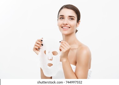 Beauty Skin Care Concept - Beautiful Caucasian Woman Applying Paper Sheet Mask On Her Face White Background.