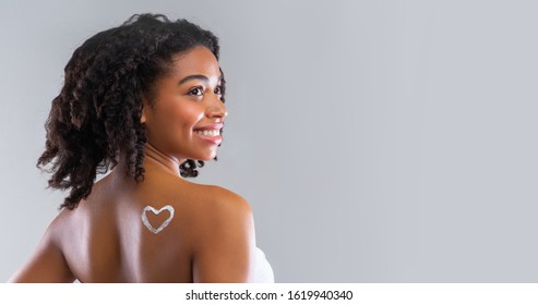 Beauty Skin Care. Cream In Heart Shape On Black Girl Shoulder, Grey Studio Background, Panorama With Copy Space