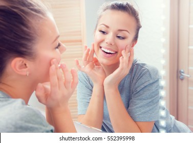 Beauty Skin Care. Young Beautiful Teenage Girl Touching Her Face Before The Mirror, Enjoying Her Clean Skin. Pretty Woman Touching Her Cheek And Smiling. Perfect Pure Skin. Fresh Clean Skin. Skincare