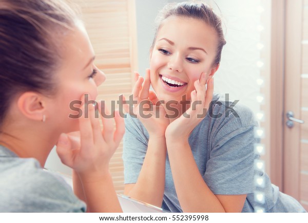 美容肌のケア 鏡の前で顔を触れ きれいな肌を楽しむ若い美しい10代の女の子 彼女の頬に触れ微笑む美しい女性 完璧な純粋な肌 新鮮で清潔な肌 スキンケア の写真素材 今すぐ編集