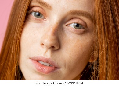 Beauty, Skin And Hair Care Concept. Close Up Shot Of Beautiful Redhead Girl With Perfect Clean Skin, With Freckles, No Make Up, Looking At Camera, Standing Over Pink Background.