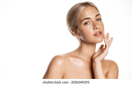 Beauty skin. Head and shoulders of blond woman model, touching glowing, hydrated facial skin, apply toner, skin cream or lotion for healthy look, after shower portrait, white background.