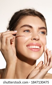 Beauty And Skincare Concept. Smiling Woman Applying Argan Oil Essential, Balance Skin Tone With Vitamin C And Aloe Vera C-Serum Product, Looking Satisfied, White Background.