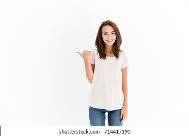 Beauty smiling brunette woman pointing away and looking at the camera over white background