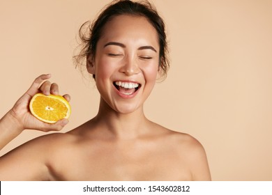 Beauty. Smiling Woman With Radiant Face Skin And Orange Portrait. Beautiful Smiling Asian Girl Model With Natural Makeup, Healthy Smile And Glowing Hydrated Facial Skin. Vitamin C Cosmetics Concept