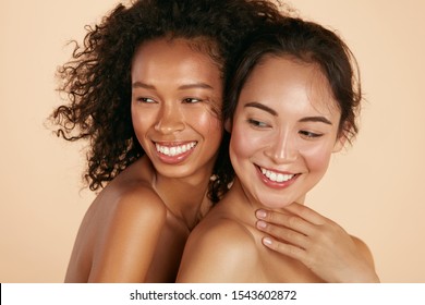 Beauty. Smiling women with perfect face skin and natural makeup portrait. Beautiful happy asian and african girl models with different types of skin on beige background. Spa skin care concept