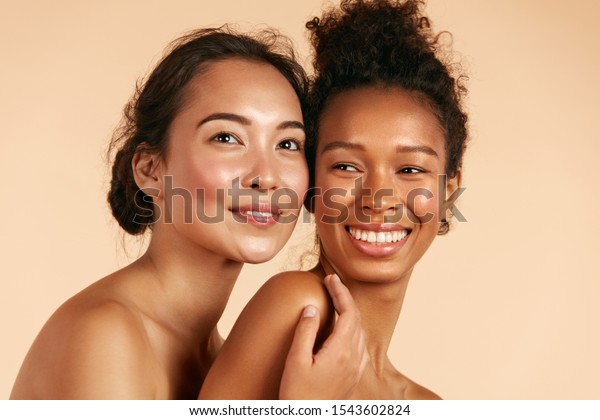 美人 完璧な顔の皮膚と自然なメイクのポートレートを持つ笑顔の女性 ベージュ背景にさまざまな種類の肌を持つ美しいアジアとアフリカの少女モデル スパスキンケアのコンセプト の写真素材 今すぐ編集