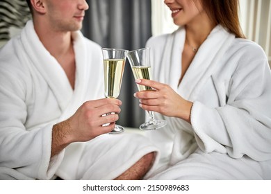 Beauty, Spa, Healthy Lifestyle Concept. Beautiful Young Couple In Bathrobes Relaxing At Luxury Hotel Room. The Boy And The Girl Are Resting In A Cozy Place And Drinking Wine. Wellness Theme