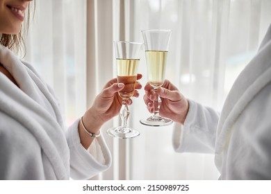 Beauty, spa, healthy lifestyle concept. Beautiful young couple in bathrobes relaxing at luxury hotel room. The boy and the girl are resting in a cozy place and drinking wine. Wellness theme
