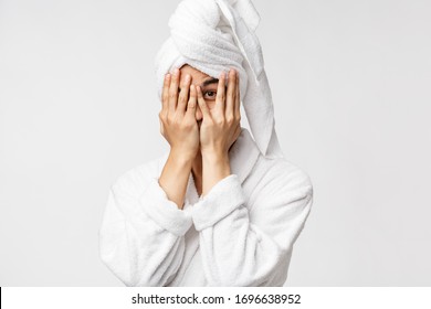 Beauty, Spa And Leisure Concept. Funny Asian Man In Bathrobe And Bath Towel Over Head, Coming From Shower, Hiding Face Behind Hands And Peeking With One Eye Curious, White Background