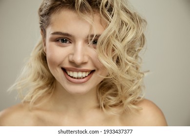 Beauty Studio Portrait Of Young Happy Optimistic Cheery Beautiful Blonde  Woman With Perfect Skin, Make Up And Hairstyles, Posing Naked Isolated Over Grey Wall Background. 