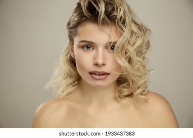 Beauty Studio Portrait Of Young Happy Optimistic Cheery Beautiful Blonde  Woman With Perfect Skin, Make Up And Hairstyles, Posing Naked Isolated Over Grey Wall Background. 