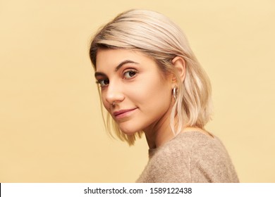 Beauty, Style And Fashion Concept. Attractive Twenty Year Old Female With Nose Ring And Dyed Bob Hair Posing Isolated Looking At Camera With Enigmatic Alluring Smile, Dressed In Cashmere Sweater