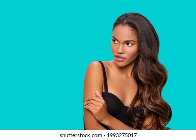 Beauty styled Portrait of a young African American woman. Hair. Fashion black girl with Curly Hair posing in the studio on a turquoise background. Isolated. Studio shot. Makeup.         