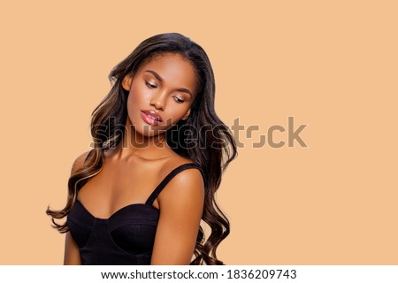 Beauty styled portrait of a young African - American woman. Fashion African - American girl with curly hair posing in the studio on a beige background. isolated. Studio shot.                          