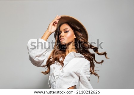 Beauty styled Portrait of a young black Woman in profile, model wears a camel color hat. makeup. Fashion African American Girl with Curly Hair posing in the Studio on a light background. Studio shot 