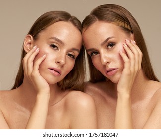 Beauty twins models young women Beautiful and young twin sisters posing with natural make-up with gathered hair in a studio with freckles 