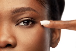 Beauty, Vision And People Concept - Close Up Of Face Of Beautiful Young African American Woman Pointing To Her Eye Over White Background