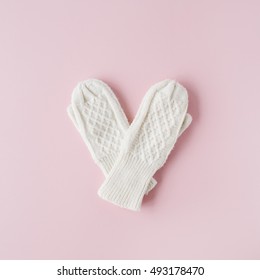 beauty white feminine knitted mittens on pink background. flat lay, top view