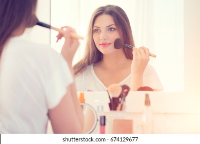 Beauty Woman Applying Makeup. Beautiful Girl Looking In The Mirror And Applying Cosmetic With A Big Brush. Girl Gets Blush On The Cheekbones. Powder, Rouge