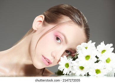 Beauty woman. Close up shot of a beautiful girl with gentle makeup and white chrysanthemum flowers. Beauty concept. Cosmetics and Perfumery. Women's health.