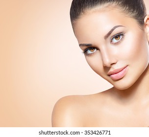 Beauty Woman Face closeup. Beautiful brunette young spa model girl with perfect skin. Skin care concept. Fresh Clean Skin. Portrait of female looking at camera and smiling. Beige background
