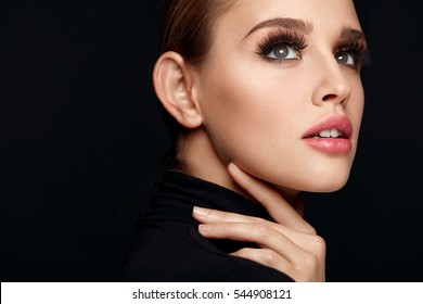 Beauty Woman Face. Portrait Of Beautiful Sexy Young Female With Perfect Facial Makeup, Soft Fresh Healthy Skin And Thick Long Black Eyelashes. Glamorous Girl On Black Background. High Resolution