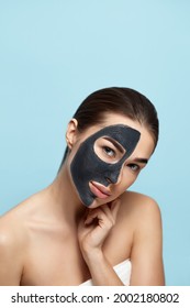 Beauty Woman Face Skin Care Mask. Portrait Of A Beautiful Female With A Black Mask Of Clay On Face .  Spa Treatment . Girl Model With Moisturizer Cosmetic Mask Touches Her Face.