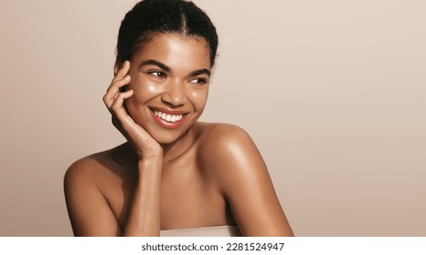 Beauty woman with perfect skin, applies daily care cream, moisturizer, brown background.