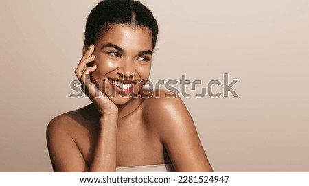 Beauty woman with perfect skin, applies daily care cream, moisturizer, brown background.