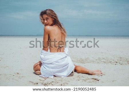 Beauty woman posing in the beach bikini, cute, fashion model, blonde hair, skin tan, wild hair, white dress, kimono, tattoo hand and body, tanning, skin tan, happy face, sea