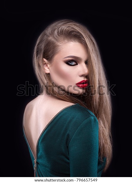Beauty woman with professional makeup and\
gorgeous hair. Beautiful face with young clean skin, perfect\
eyebrows, cat eyes makeup and red lipstick. Girl wearing a dress\
with naked back. Femme\
fatale.