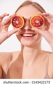 Beauty. Woman With Radiant Face Skin Squeezing Orange In Hand Portrait. Beautiful Smiling Asian Girl Model With Natural Makeup, Glowing Facial Skin And Citrus Fruit. Vitamin C Cosmetics Concept