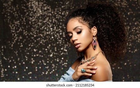 Beauty woman with a set of jewelry and afro hair. Beautiful girl in a necklace with a earrings, ring. Beauty and an expensive accessories, bijouterie.