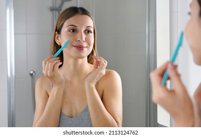 Beauty woman shaving her face by razor at home. Pretty girl using razor on bathroom. Facial hair removal.