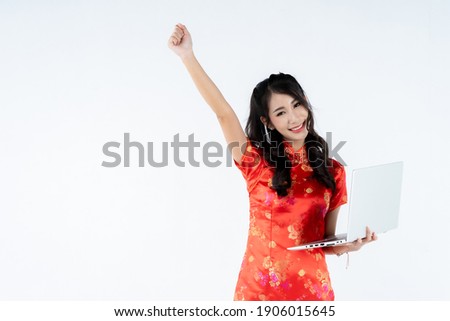 beauty woman wear cheongsam and hand sign rise upward meaning victory, fight hold notebook laptop computer in chinese new year on white background