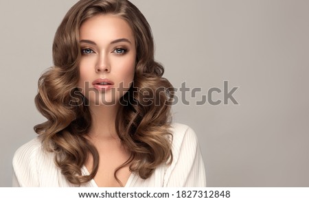 Beauty  woman in a white shirt with long  and   shiny wavy  hair .  Beautiful blonde   woman model with curly hairstyle .