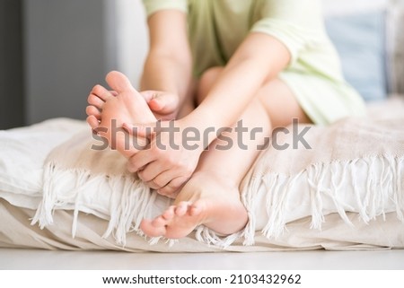 Beauty women's legs with smooth skin in the home interior, foot care and self-massage, unrecognizable person