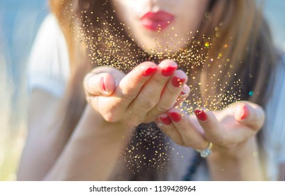 Beauty Young Woman Blowing Magic Gold Glitter Dust From Her Hand.