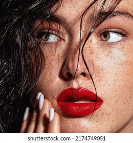 beauty young woman face with a lot of freckles and red lips, hand near face, close up
