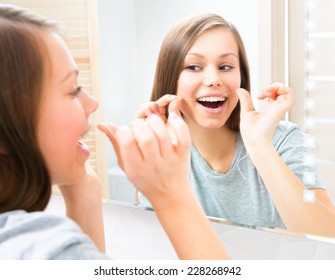 Beauty Young Woman Flossing Her Teeth At Home. Pretty Teenage Girl Using An Interdental Brush Smiling At The Mirror Enjoying Beautiful White Teeth. Healthcare Of Mouth And Dental Floss. Dental Hygiene