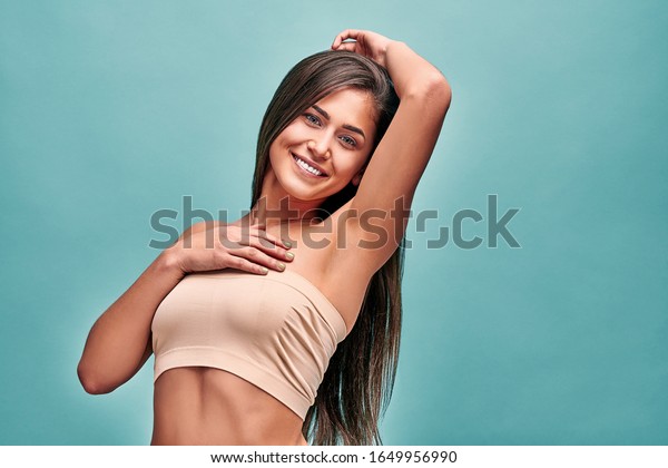 Beauty, youth, freshness and perfect skin.Armpit\
epilation, laser hair removal. Beautiful woman with long hair\
holding her arms up and showing clean underarms, depilation smooth\
clear skin in studio.