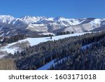 Beaver Creek Ski Resort and a view of the snow covered Colorado Rocky Mountains on a blue sky winter day with ski tracks on a distant run in the Vail backcountry