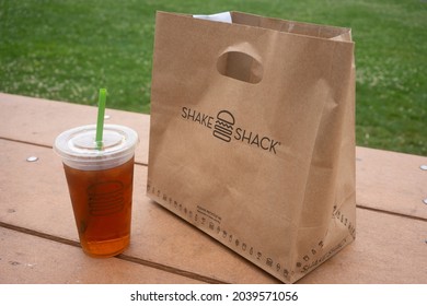 Beaverton, OR, USA - Sep 10, 2021: Closeup Of A Shake Shack Food Takeout Paper Bag And A Cup Of Iced Tea On A Picnic Table In A Park In Beaverton, Oregon.