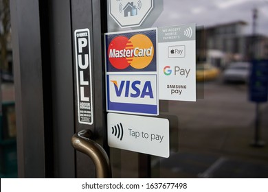 Beaverton, Oregon, USA - Jan 31, 2020: Various payment options are seen advertised at the entrance to a restaurant, including MasterCard, VISA, Apple Pay, Google Pay, Samsung Pay, and Tap to pay.