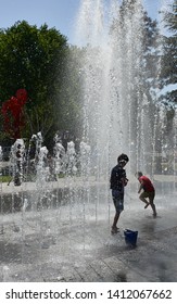 Beaverton, Oregon, USA - May 8, 2019: Children playing in spray fountains and keeping cool in hot weather.